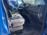 the interior of a blue truck with the door open and the driver ' s seat down
