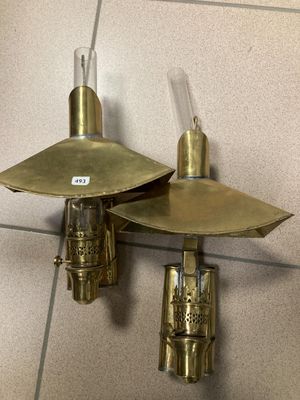 pair of brass wall sconces on a tiled wall in a bathroom