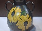 un vase noir orné de fleurs jaunes, posé sur une table