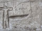 des sculptures représentant un homme sur une croix, sur un mur de pierre