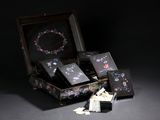 a small doll sitting in a suitcase next to a pile of cards