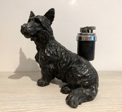 a black dog statue next to a lighter on a table