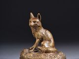 une statue en bronze représentant un chat assis sur un rocher