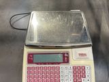 une balance posée sur une table, avec un clavier rouge dessus