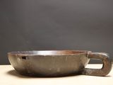 a metal bowl with a handle sitting on a table