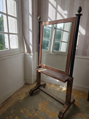 un miroir posé sur un pied dans une pièce dotée d'une fenêtre
