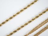 a close up of a group of gold chains on a white surface