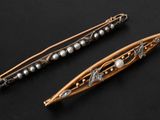 two antique hair pins with pearls on them sitting on a black surface