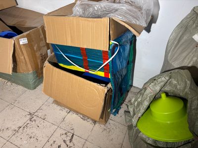 a pile of boxes sitting on the floor next to a trash can