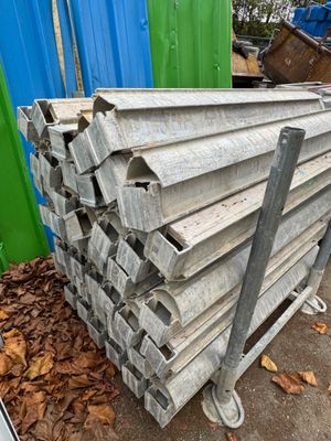 un tas de bois posé par terre à côté d'un conteneur bleu