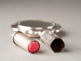 two lipsticks sitting next to a mirror on a table
