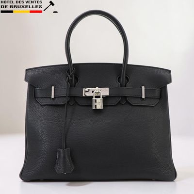 un sac à main en cuir noir posé sur une table blanche