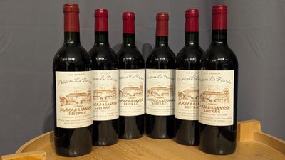 four bottles of wine are sitting on a wooden barrel