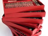 stack of red boxes with silverware in them on a white surface