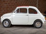 a small white car parked in front of a brick wall