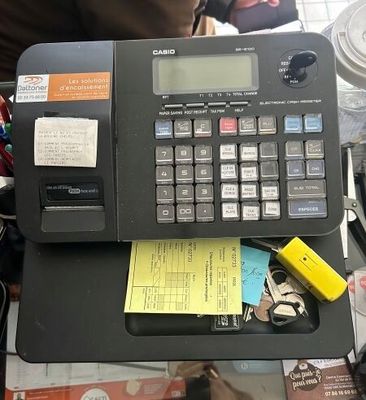 une calculatrice posée sur un bureau recouvert d'une pile de papiers