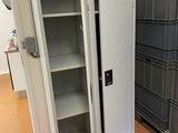une grande armoire métallique dont la porte est ouverte, dans une pièce