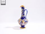 un vase bleu et or posé sur une surface blanche