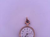 a small gold pocket watch on display on a white surface