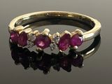 an image of a gold ring with pink stones on a black surface