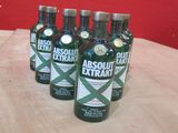 Six bouteilles d'Absolut Extra sont posées sur une table devant un mur rouge.