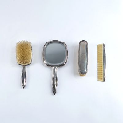 quatre types différents de brosses et de peignes à cheveux posés sur une surface blanche