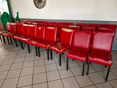 des rangées de chaises rouges dans une pièce où est accrochée une horloge au mur
