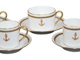 four coffee cups and saucers with gold trims on a white background