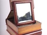 books stacked on top of each other with a mirror on top of them