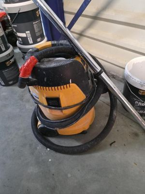 un aspirateur jaune et noir posé par terre à côté de quelques seaux de peinture