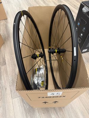 two bicycle wheels in a cardboard box on a wooden floor