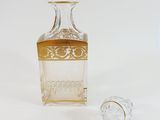 a clear glass bottle with a gold lid next to a small glass bottle