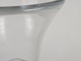 a clear glass vase with a silver rim on a white surface