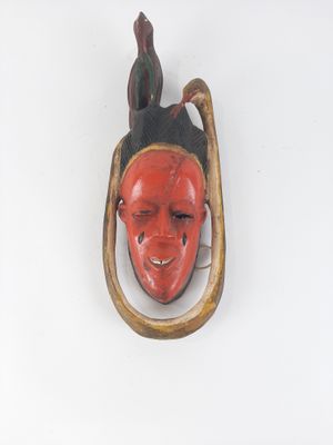 a red mask hanging on the wall with a bird on it