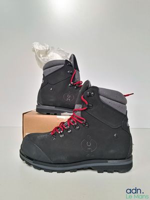 des chaussures de randonnée grises avec des lacets rouges, posées sur une boîte
