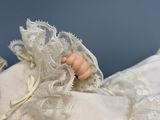 a close up of a doll with a white dress on