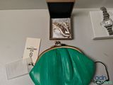 a green purse sitting on a table next to a watch