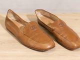 pair of tan loafers on a wooden surface with a white background