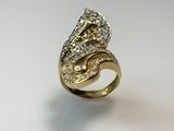 gros plan d'une bague en or avec des diamants sur une surface blanche