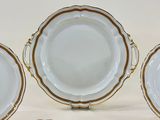 four white and gold plates with gold trims on a white surface