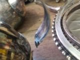 a silver tea pot sitting on a table next to a silver plate