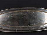 an oval silver tray on a black surface with a black background