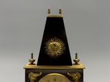 une horloge noire et dorée sur laquelle est représenté un soleil