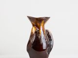 a brown vase that is sitting on a white surface