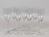 six clear wine glasses lined up in a row on a white surface