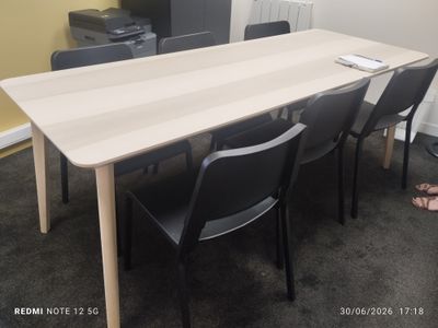 une longue table sur laquelle se trouvent des chaises et une imprimante