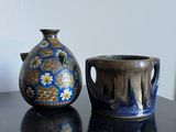 deux vases posés sur une table, avec un tableau accroché au mur en arrière-plan