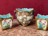 trois vases posés sur une table, sur fond rouge