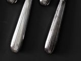 four silver spoons and two silver spoons on a black table
