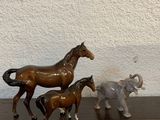 trois figurines de chevaux et un éléphant posés sur une table